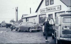 three 1950s cars with woman in front of Kenai Commercial Co.