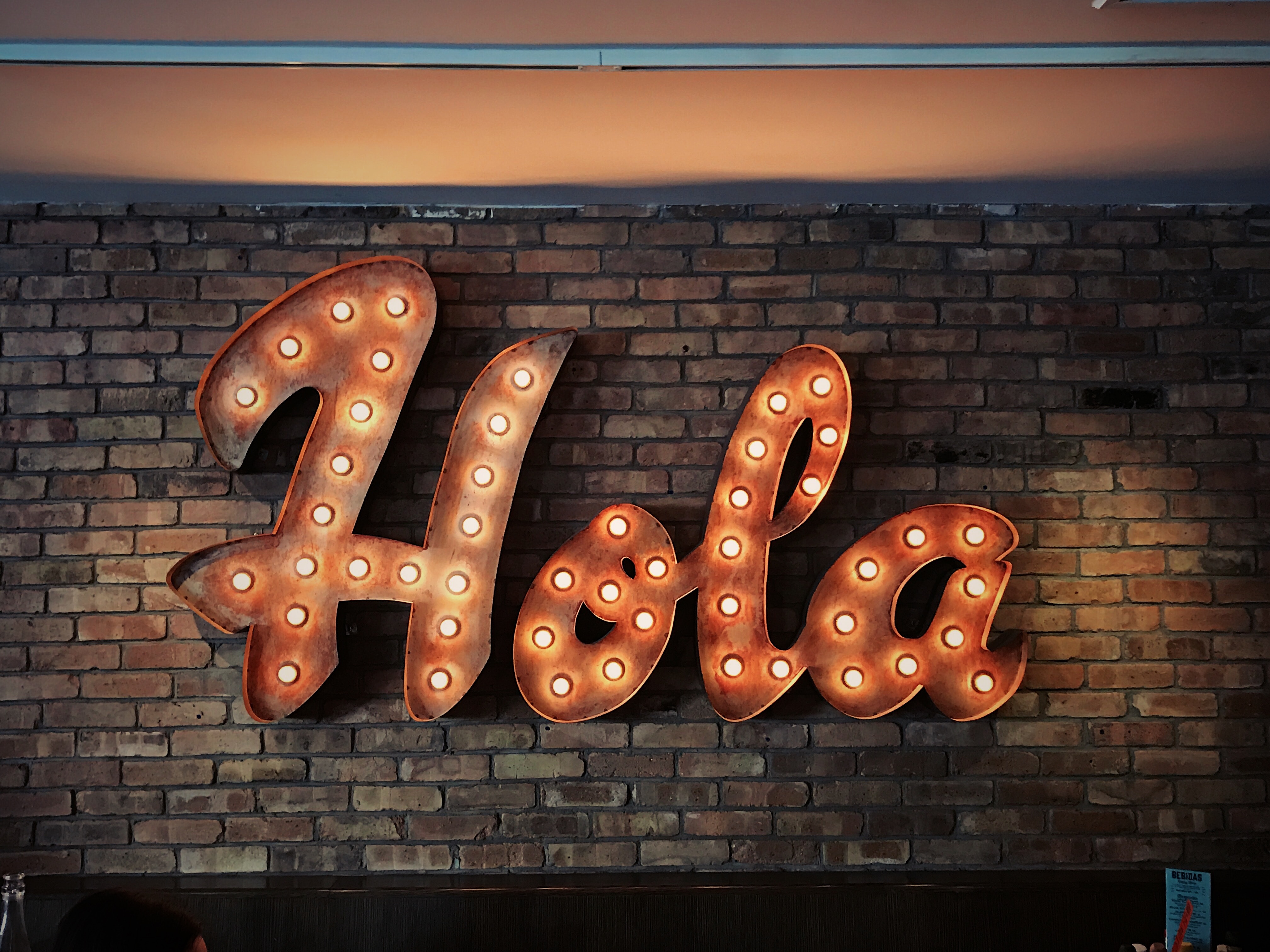 an artistic illuminated metal sign saying "Hola" 
