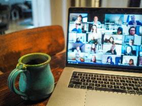 Zoom room visible on laptop on table with coffee cup