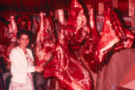 Betty Karsten cutting moose meat in garage, Soldotna 1950's