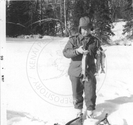 Calvin Fair holding up his ice fishing catches, Kenai Peninsula 1966