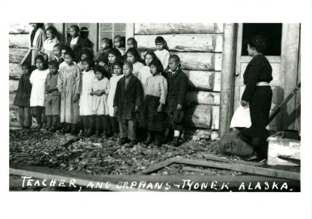 Group photo of teacher and 23 Native Alaskan orphans in front of a building, Tyonek 1927