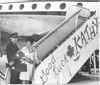 Kathy Fuhriman and pilot Norm Israelson boarding plane with "Good Luck Kathy" sign, Kenai 1960's